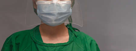 Asian female nurse wears surgical masks, green gown, face shield, and a stethoscope around the neck. Stand with elegance and confidence. Safeguarding yourself against the Coronavirus concept.の写真素材