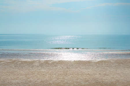 The coast is quiet in the morning, the sunlight shines on colored water. The soft indigo is sparkling. The blue sky is clean and clear. Feeling fresh, calm, and soft. There is a copy space on top.の写真素材