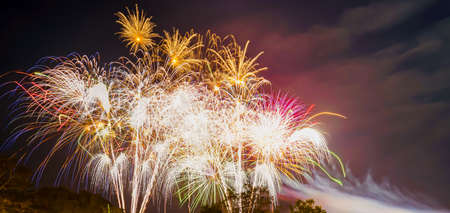 A low angle shot of many fireworks in groups at night. There is dazzlingly lit and colorful. Feeling fun and happy. The idea for celebration wallpaper with copy space on the right of the picture.の写真素材