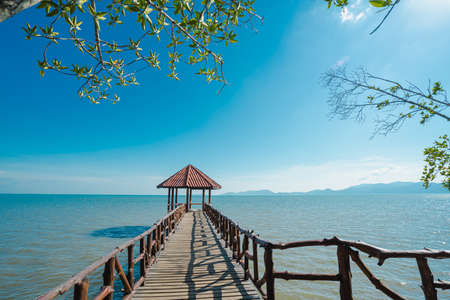 Front view of the iron pavilion in the sea. There is wooden bridge into the blue ocean in the morning with sky is bright blue and white clouds. The idea for cold background and copy space on the top.の写真素材