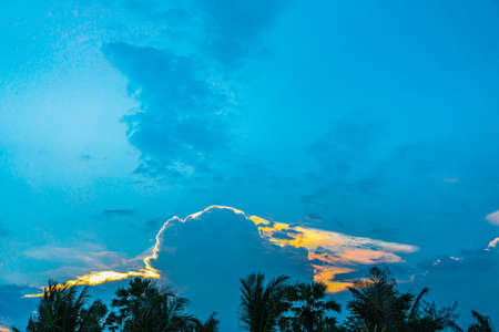 A photograph of  Iridescent Pileus Cloud in the twilight colored sky in the evening. The bellow edge of the image is a black large mountain. Feeling calm and relax. There is a copy space on topの写真素材