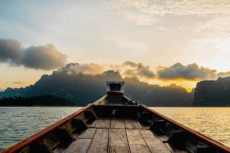 View from a wooden Thai style boat in dam with white big stonds. There are many limestones in the early morning with sunrise. Feeling fresh and relax. Ideas for traveling background with copy space.の写真素材