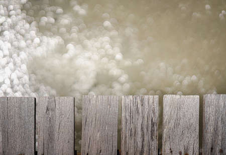 Picture of pale white old wooden planks in a soft tone. There is a line of texture with low contrast. Blur backdrop is a bokeh of water with warm light. The idea for vintage wallpaper with copy space.の写真素材