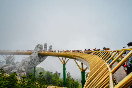 DA NANG, VIETNAM - 25 MARCH 2019: Many tourists walk on the Golden bridge on a foggy morning. There was old white cement in the shape of a large hand and the bridge was golden with lush trees below.のeditorial素材