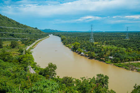 The landscape of a large river flowing through the village area and a large electric poles running...