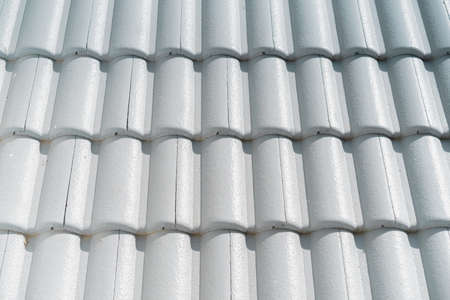 Photographs of old white tiled arranged neatly on the roof on a sunny day. There are straight lines and curves with textures. Feeling strong and safe. Ideas for construction with copy space.の写真素材