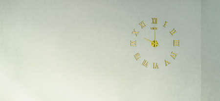 The golden color clock on the white cement background. It's a Roman numeral in an elegant design. At that moment it was ten o'clock in the morning. Idea for timing background with copy space on top.の写真素材