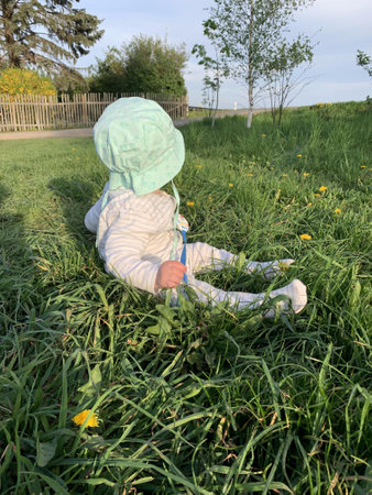 A girl in a medical mask is sitting on the grass in the garden.の写真素材