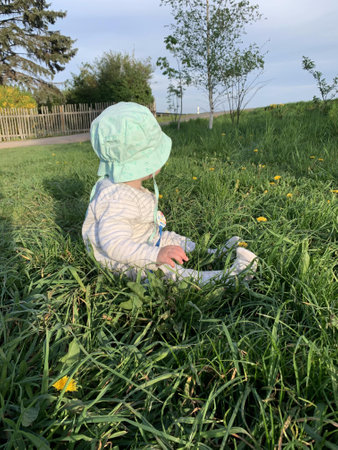 Baby sitting in the grass and playing with a stethoscope.の写真素材