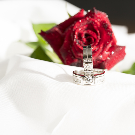 Diamond ring jewelry with rde rose flower on white satin background./ daimond ring.の写真素材