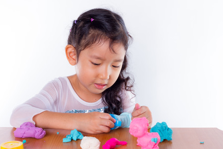 Little girl is learning to use colorful play dough on white backgroundの写真素材