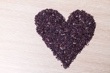 heart shape of rice berry grains on wooden backgroundの写真素材