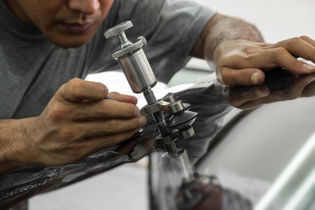 Mechanic using repairing equipment to fix damaged windshield