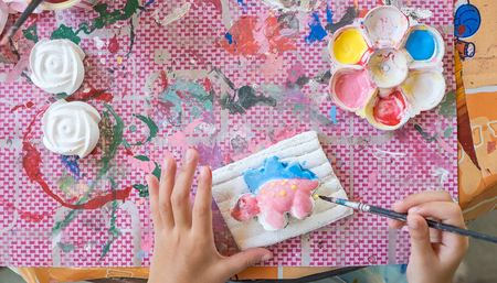 Close up Little hands of kid painting on the plaster statue