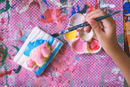 Close up Little hands of kid painting on the plaster statueの写真素材