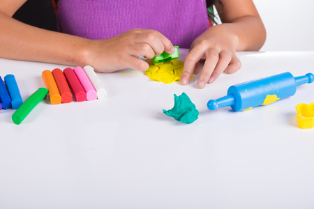 Little hand of kid learn to play coloful clay on white tableの写真素材