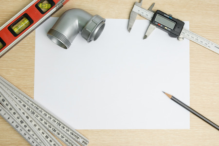 Top view of ruler, water level, vernier caliper, pencil and plastic angle pipe on blank paper background.の写真素材