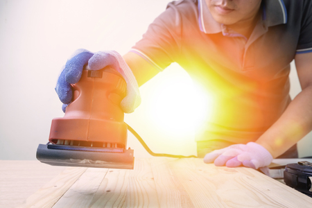 Carpenter using sander machine sanding on pine wood surfaceの写真素材