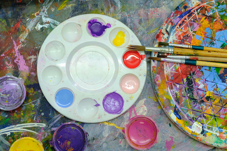 Close up of paint brushed and water colour plate on workshop table.の写真素材