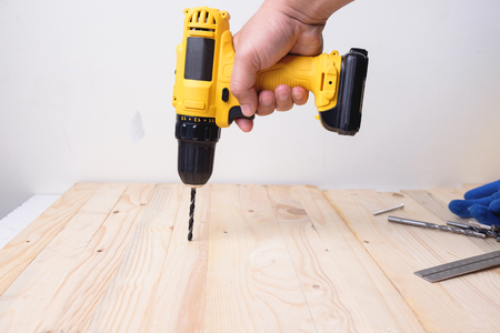 Craftsman working with power drill on wooden plankの写真素材