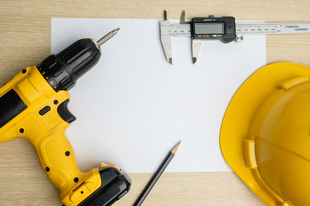 Top view of power drill, pencil, vernier caliper, safety helmer on blank paperの写真素材