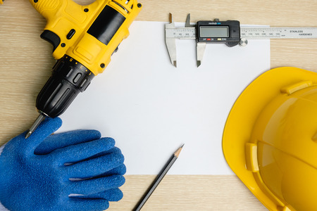 Top view of power drill, pencil, vernier caliper, safety helmet on blank paperの写真素材