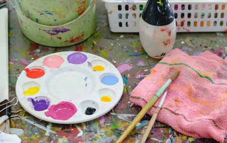 Close up of paint brushed and water colour plate on workshop table.の写真素材