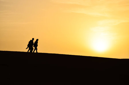 Silhouette of a Group of People Walking in the Sahara Desert During Sunriseの写真素材