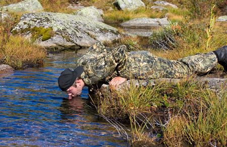 Man drinks water from a streamの写真素材