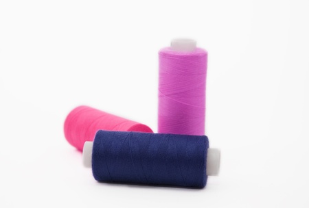 Three bobbins of colour threads isolated on white backgroundの写真素材