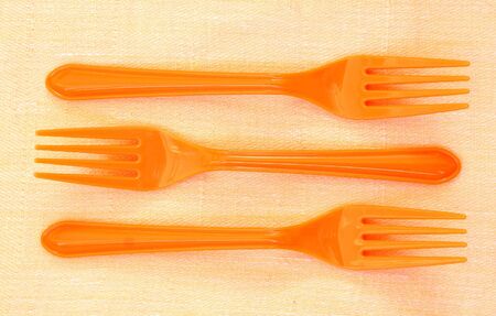 Three orange plastic forksの写真素材