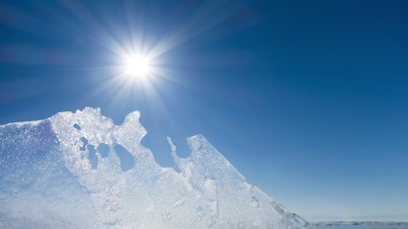 A transparent ice against the bright sun. Blue sky.の写真素材