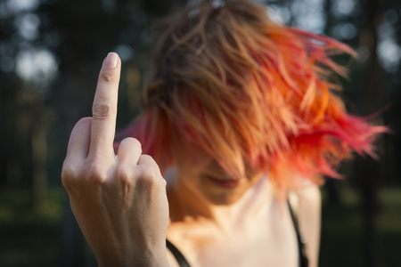 Red-haired girl showing middle finger gesture. Redhead woman showing a fuck you off signの写真素材