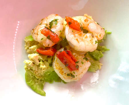 Luxury starter of poached prawns in garlic butter and parsley on a bed of fresh avocadoの写真素材