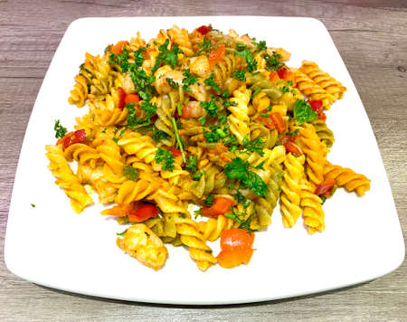 Fiery prawn and red peppers sautÃ©ed in garlic butter and parsley sauce mixed with a spicy chilli pesto sauce and try-color fusilli pasta, a wonderful Italian specialityの写真素材