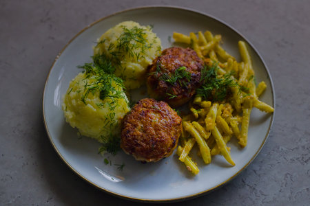 Classic Polish cuisine: pork mince burgers, mashed potatoes, yellow wax beans, breadcrumb-topped, garnished with finely chopped dill.の写真素材