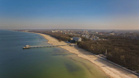 KoÅobrzeg pier on a sunny February afternoon. Windless weather, calm sea without a single wave, tourists strolling on the pier. Serene atmosphere captured in a stock photo.の写真素材