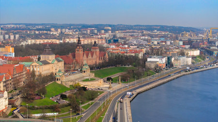 March aerial drone footage captures Szczecin's Odra River, Szczecin Castle Route, cars, WaÅy Chrobrego, National Museum, Provincial Office building, Port of Szczecin, docked ships, cranes, port infrastructure, and Grodzka Island.の写真素材