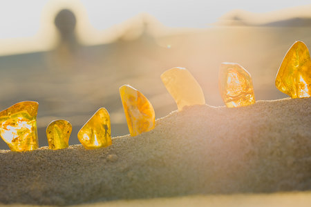 Sunset warms the KoÅ‚obrzeg shore, lighting up smooth amber stones in yellow and honey hues with...