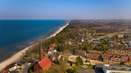 Drone photo of Sarbinowo, Poland, showing coastline, church and golden beach on sunny March afternoon.の写真素材