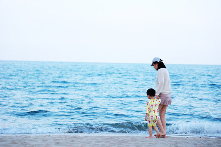 Mother and son playing on the beach at the day time. Concept of friendly family.の写真素材