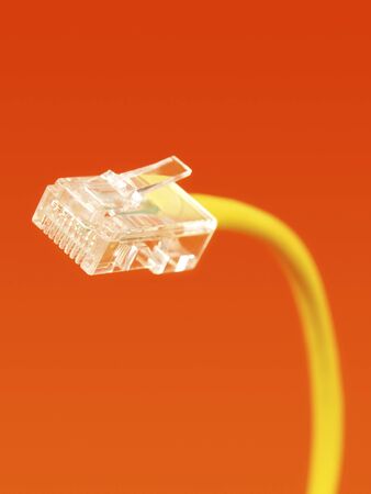 Yellow network cable plug on orange backgroundの写真素材