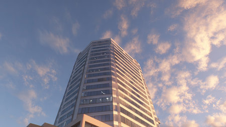 A stunning perspective of a modern skyscraper soaring towards a colorful evening sky, with wisps of clouds reflecting warm sunset hues, creating a vibrant urban scene.の素材
