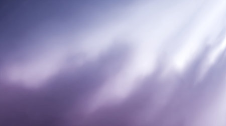 Soft and tranquil abstract image showcasing a dreamy cloudy sky in shades of purple and gray with gentle rays of light illuminating the scene.の素材