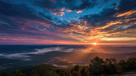 Experience the awe of a stunning sunrise illuminating a mountain range, with vibrant colors painting the sky and soft fog resting in the valley below.の素材