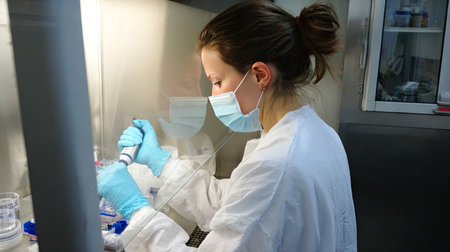 A female scientist is focused on her research in a laboratory, using a pipette to handle samples in a clean and sterile environment, ensuring precision.の素材