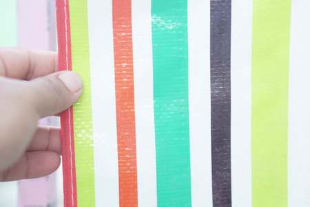 A close-up view of a colorful striped surface held by a hand, showcasing vibrant hues and playful patterns ideal for various creative projects and artistic ideas.の素材