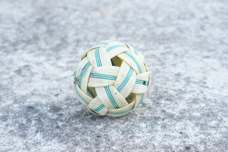 This image depicts a handcrafted woven rattan ball resting on a textured gray surface, highlighting the intricate design and traditional craftsmanship of the object.の素材