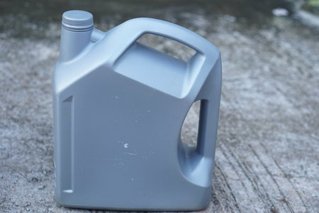This gray plastic container is designed for storing liquids or oils, featuring a sturdy handle for easy transport. Ideal for utility work in garages or workshops.の素材