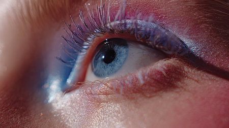 A stunning close-up captures the intricate details of an eye adorned with colorful makeup. The vibrant hues and long lashes create an artistic and glamorous look, showcasing beauty.の素材